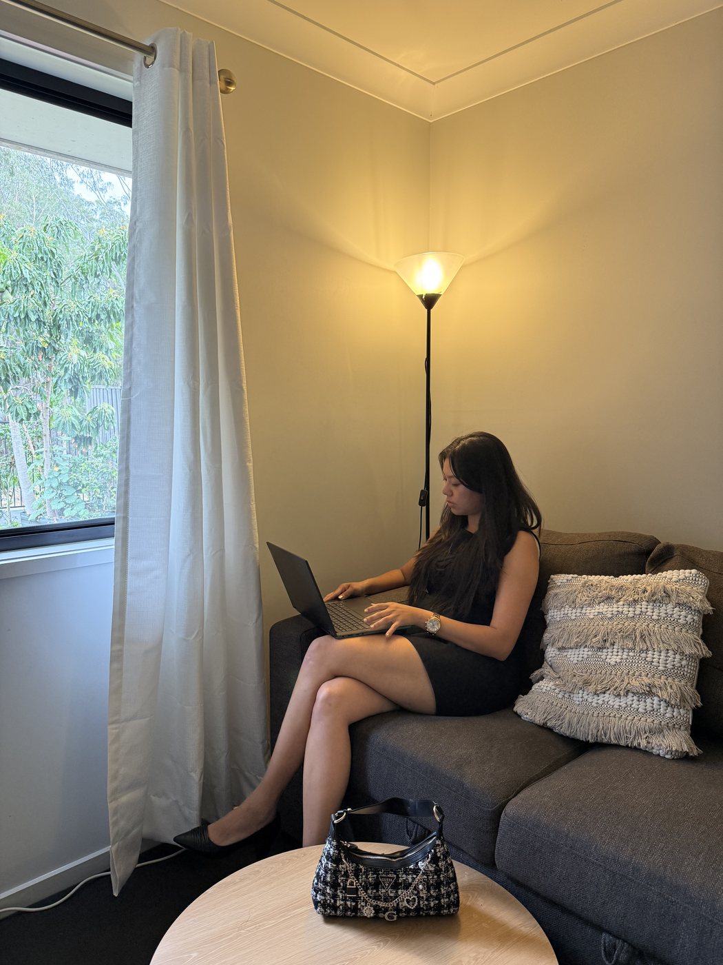 Ismriti working on a laptop on the sofa in warm lamp light
