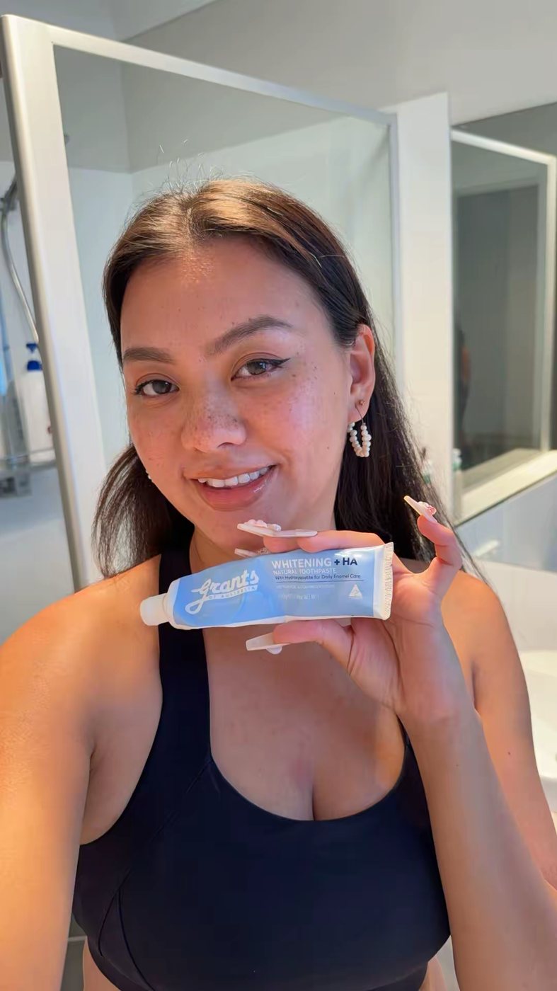 Ismriti smiling while holding a tube of toothpaste