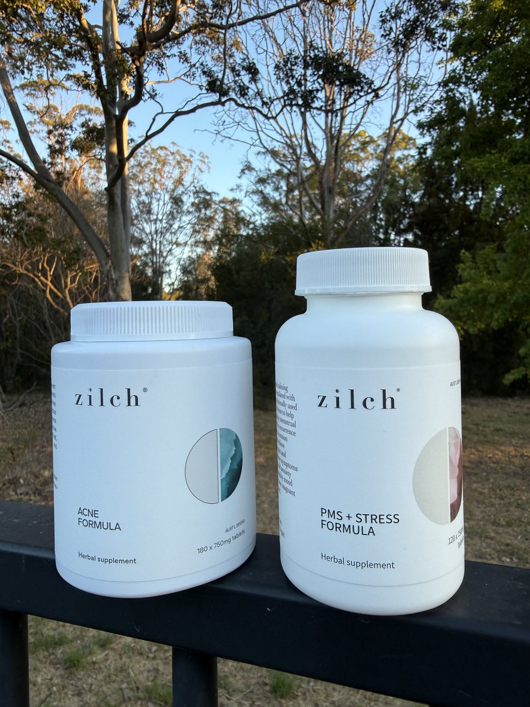 Two supplement bottles on a balcony rail with gum trees behind